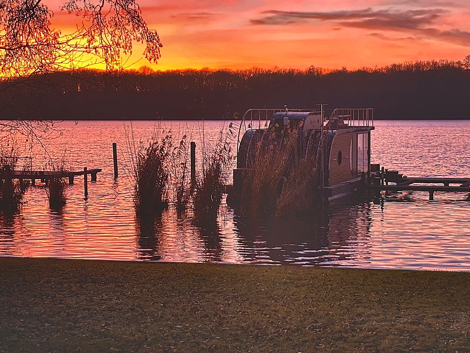 Abendrot über dem Schilfufer des Krüpelsees mit festgemachtem Boot