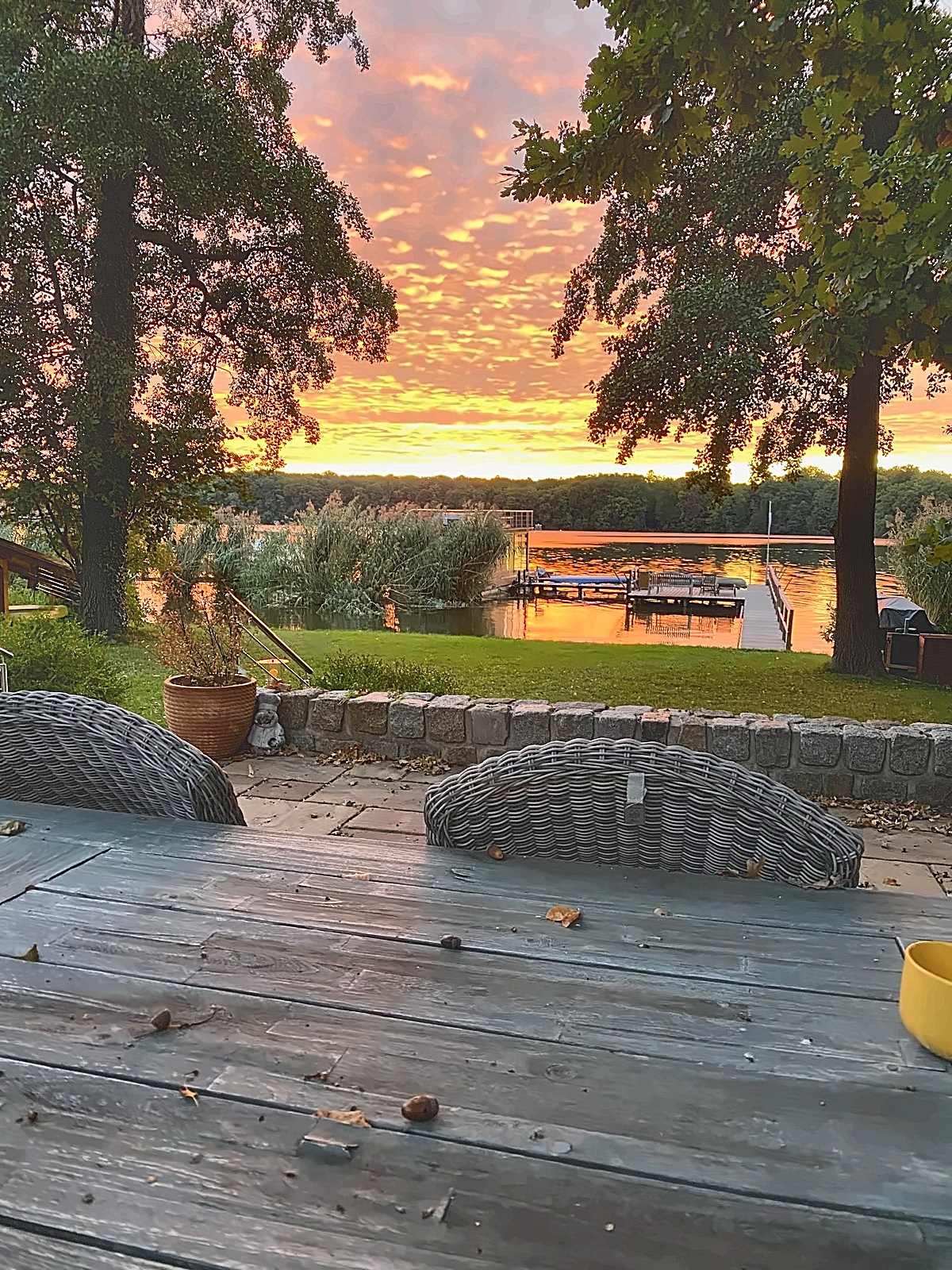 Sitzplatz im Garten mit Blick über die Wiese zum Steg am Krüpelsee in der Abendsonne